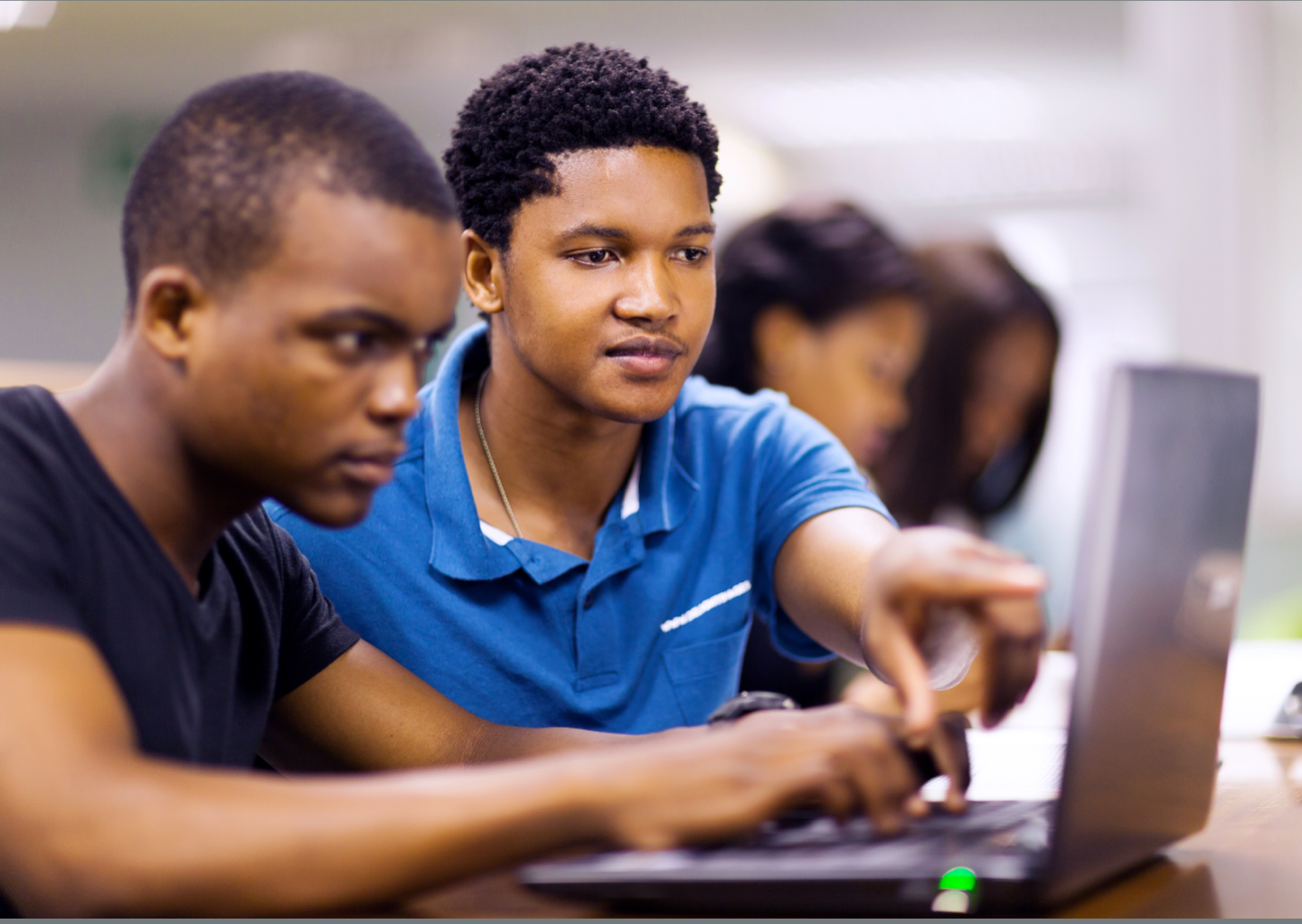 Photo of two teenage Black male students working together at a computer.